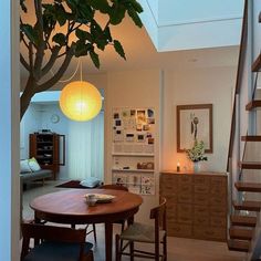 a dining room table and chairs under a tree in the middle of an open floor plan