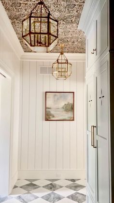 a hallway with white walls and black and white checkered flooring, chandelier hanging from the ceiling