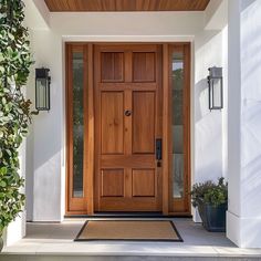 a front door with two planters on the side and an entry mat underneath it