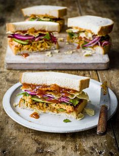 a sandwich cut in half sitting on top of a white plate next to a knife