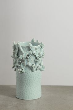 a blue vase sitting on top of a table next to a white wall and floor