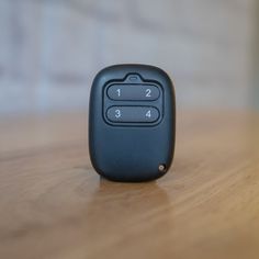 a black remote control sitting on top of a wooden table