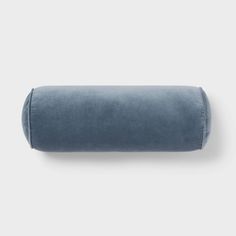 the blue velvet pillow is laying on top of a white wall and it's rolled up