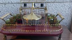 an old fashioned bar cart filled with liquor glasses and other items on top of a wooden table