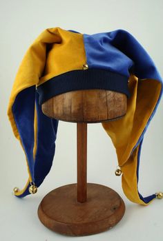 The jester was the clown of the middle ages, their hats were sometimes called the "cap' n 'bells", for the typical bells found at the end of the points. The jester has now come to stand for mirth and frivolity, a place to temporarily set aside the trials of life. Blue Gold velveteen with gold bells. One size fits all b Jester Hat Pattern Sewing, Clown Inspired Outfit, Clown Fit, 2 Color Combinations, The Jester, Clown Hat, Clown Clothes, Character Clothes, Court Jester