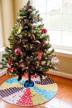 a decorated christmas tree in the corner of a room with a large window behind it