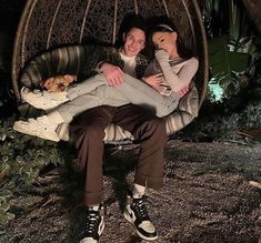 a man and woman are sitting in a swing chair with their arms around each other