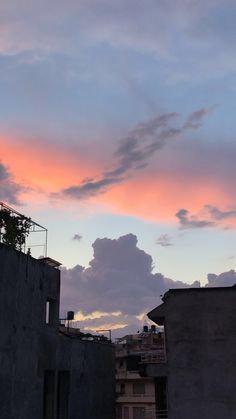 the sky is pink and blue as it sets in front of some building's