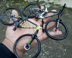 a hand holding three bikes in it's palm, with one being held up to the camera