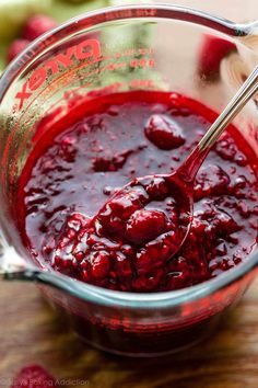 a glass bowl filled with cranberry sauce on top of a wooden table