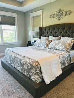 a large bed sitting in the middle of a bedroom next to a lamp and window