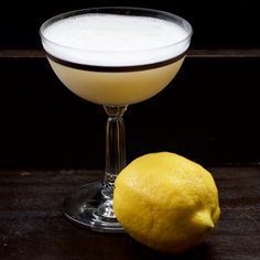 a lemon sitting next to a glass filled with white liquid and a yellow lemon on the side