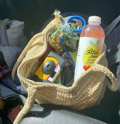 a basket filled with lots of items sitting on top of a car seat next to a bottle