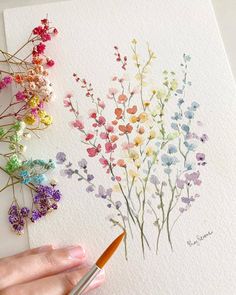 a person is painting flowers with watercolors on paper