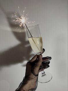 a person holding a wine glass with a sparkler in it's hand, against a white background