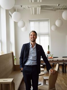 a man standing next to a wooden bench in a room filled with tables and chairs