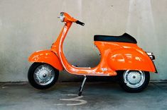 an orange scooter parked in front of a wall