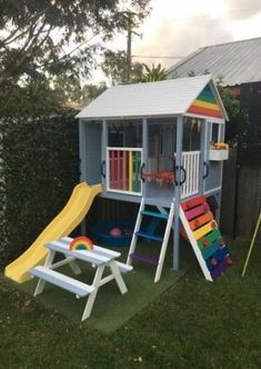 there is a small play house with a slide and picnic table in the back yard