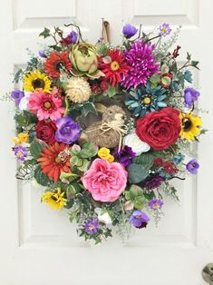 a wreath with flowers hanging on the front door