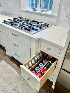 an open drawer in the middle of a kitchen counter with cupcakes inside it