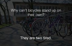 there are many bicycles parked on the side of the road and one is saying, why can't bicycles stand up on their own? they are two tired