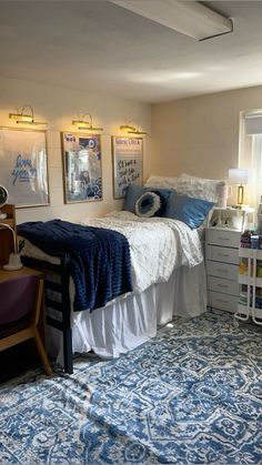 a bed room with a neatly made bed and blue rugs on the floor next to a window