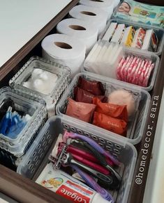 an organized drawer filled with toilet paper, scissors and other household care items in plastic containers