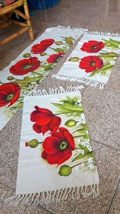 four red flowers on white tablecloths laying on the floor next to each other