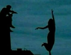 two people are silhouetted against the sky with their arms in the air