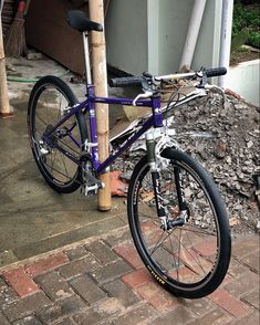 a purple bike parked next to a wooden pole