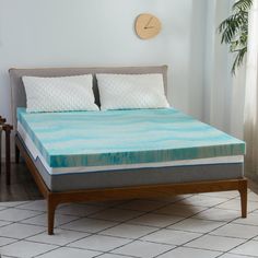 a bed with two pillows on top of it and a clock mounted to the wall