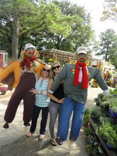 three women and one man are posing with scarecrows