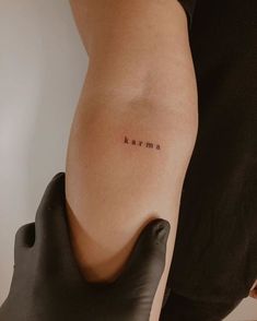 a woman's arm with the word karma tattooed on her left side ribcage