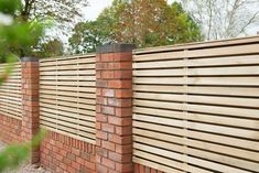 a brick wall with a wooden slatted fence on the top and bottom part