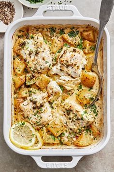 a casserole dish filled with chicken, potatoes and lemons on a table