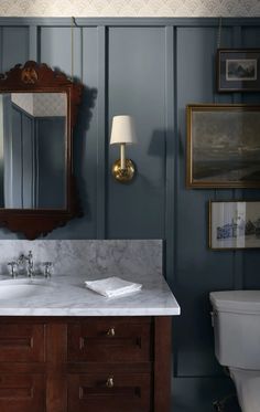 a bathroom with blue walls and white marble counter tops, along with a wooden vanity