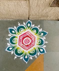 an artistic painting on the ground in front of a brick wall, with white and red designs