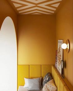 a bedroom with yellow walls and white trim on the ceiling, along with an arched window