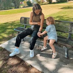 a woman sitting on top of a bench next to a little boy in front of her