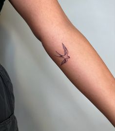 a small bird tattoo on the right forearm and arm, with an arrow in the middle