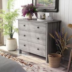 a bedroom with a dresser, mirror and potted plants on the floor in front of it