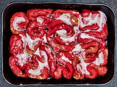 a pan filled with red peppers covered in white icing