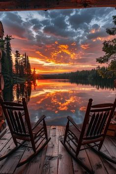 two rocking chairs sitting on top of a wooden deck next to a body of water