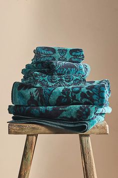 stack of folded towels sitting on top of a wooden stool