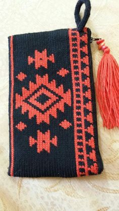 a black and red bag with tassels sitting on top of a white table