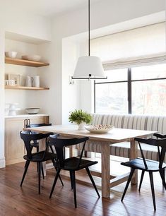 a dining room table with chairs and a bench in front of the window next to it