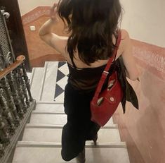 a woman with a red purse walking up stairs