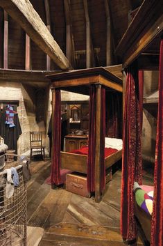 an old fashioned bedroom with wooden floors and red drapes