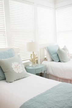 two beds in a bedroom with white and blue bedding