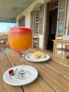 a drink sitting on top of a wooden table next to a white plate with food